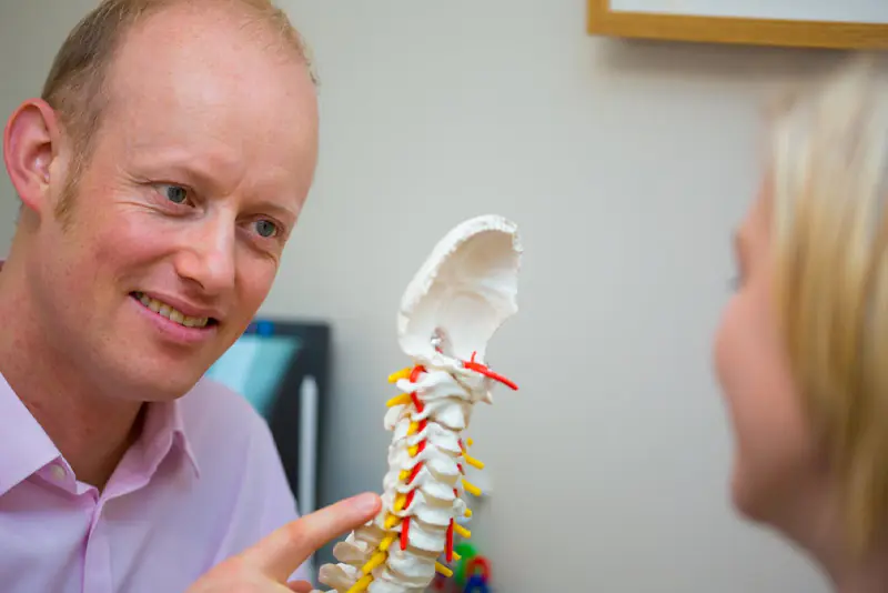 A chiropractor at The Chiropractic Centre explaining a model of the cervical spine to a patient